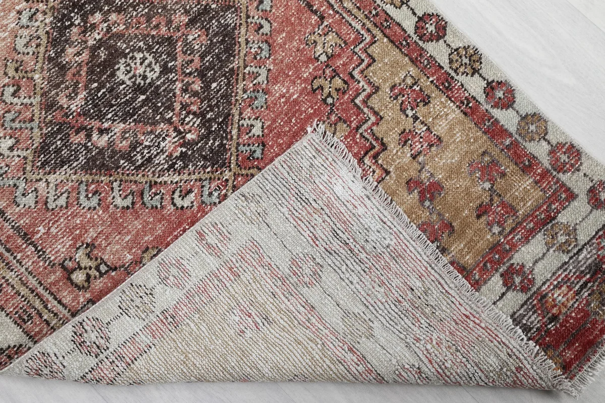 Corner of the rug folded to reveal the hand-knotted cotton foundation on the back.