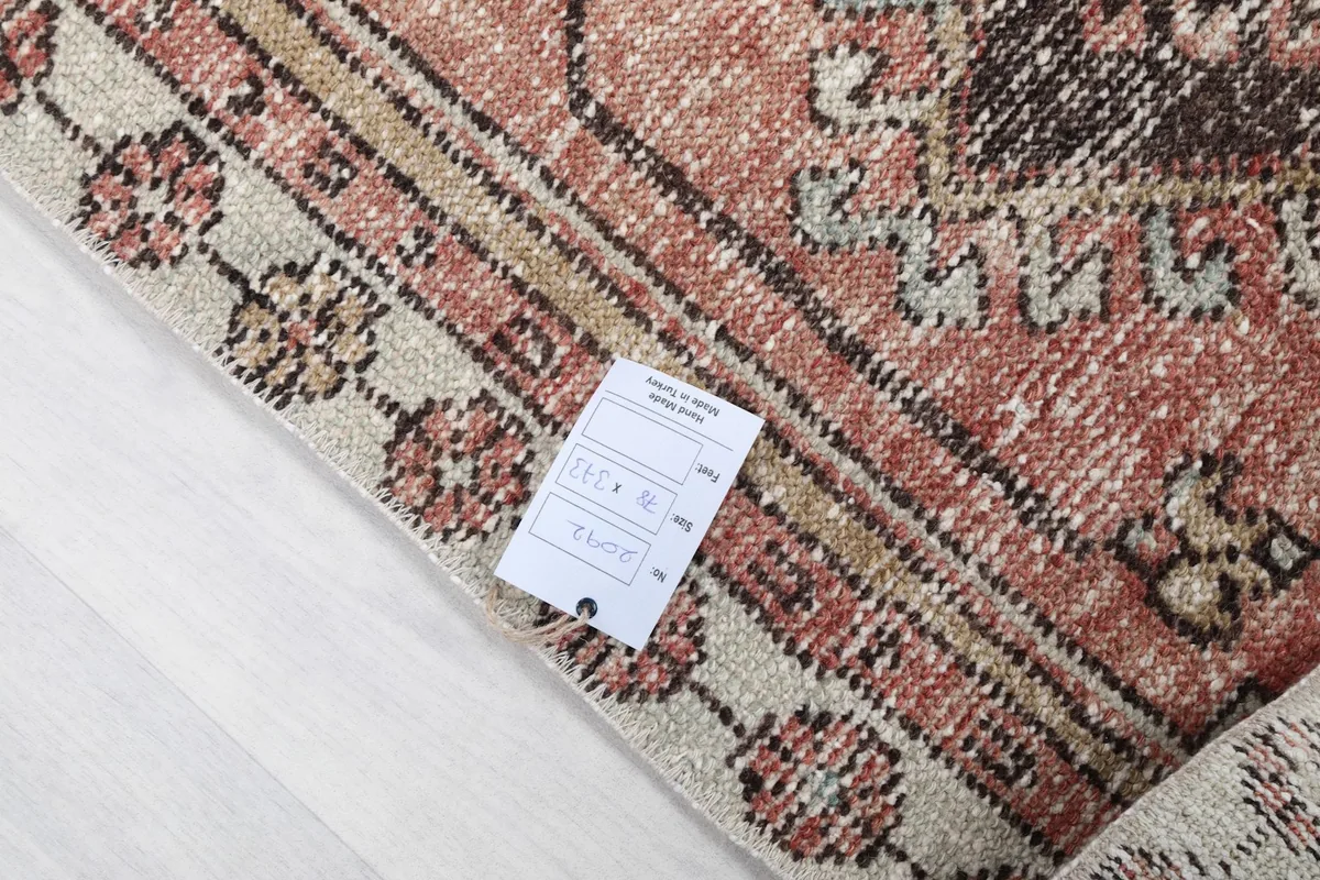 Corner of the rug with a product tag, showing the intricate knotting and fringe detail.