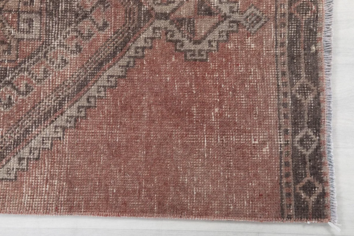 Detailed view of the faded rose field and charcoal geometric border pattern