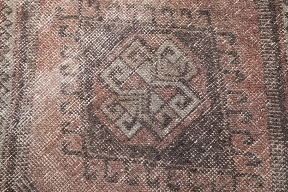 Extreme close-up of the hand-knotted wool pile and faded charcoal geometric motif