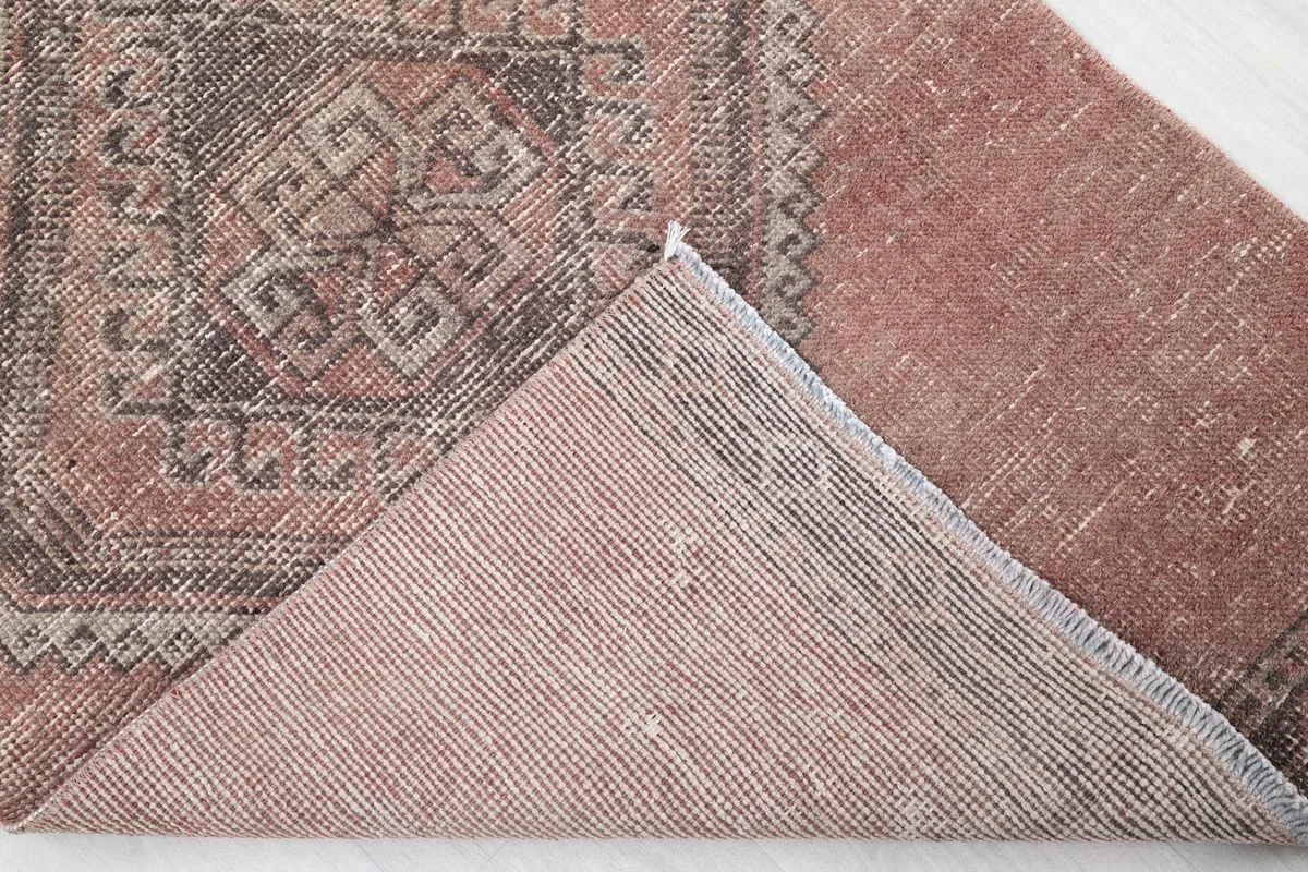 Corner of the runner folded back to show the cotton foundation and knotting