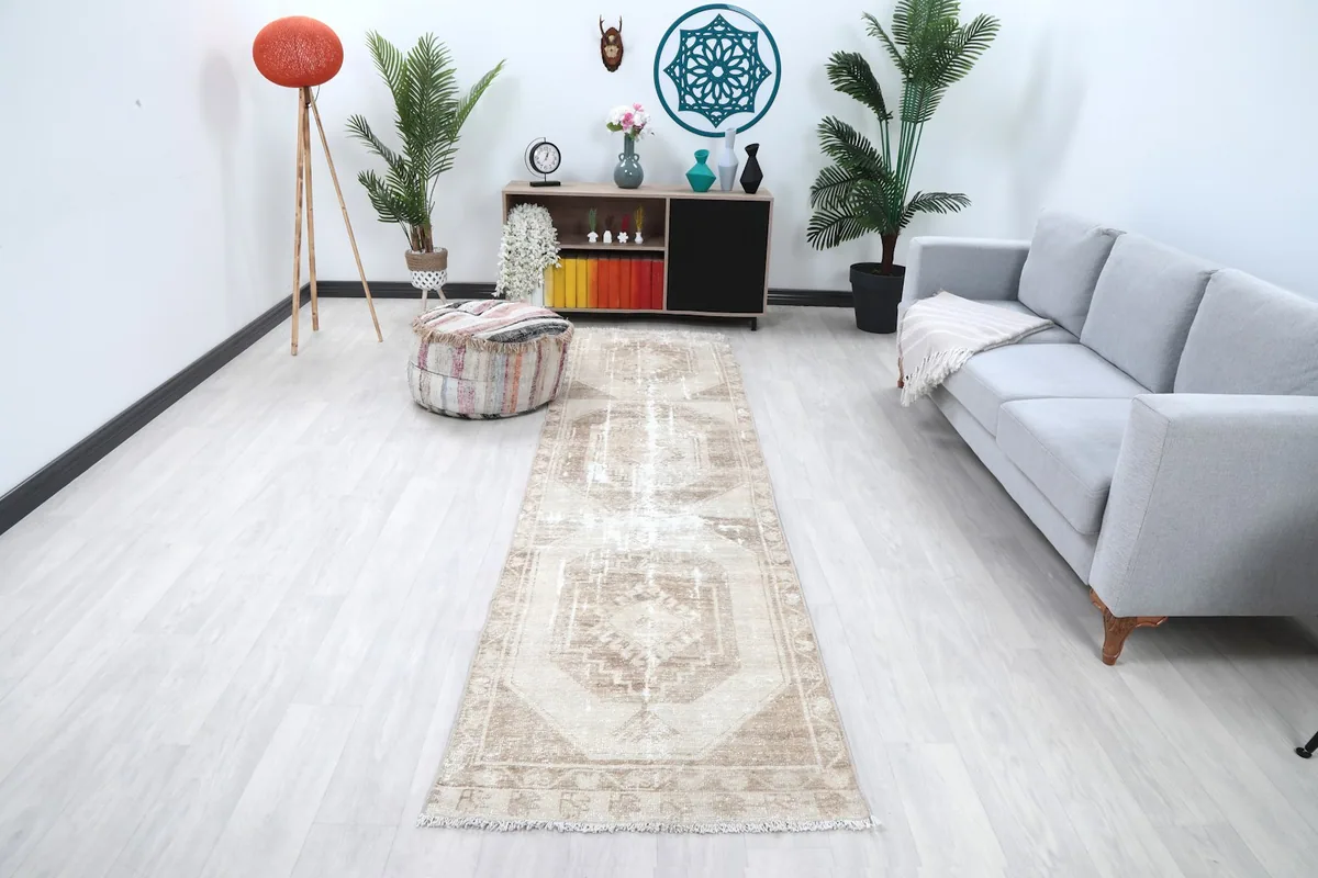 Long shot of the beige and tan runner rug in a modern living room setting with a light gray sofa and ottoman.