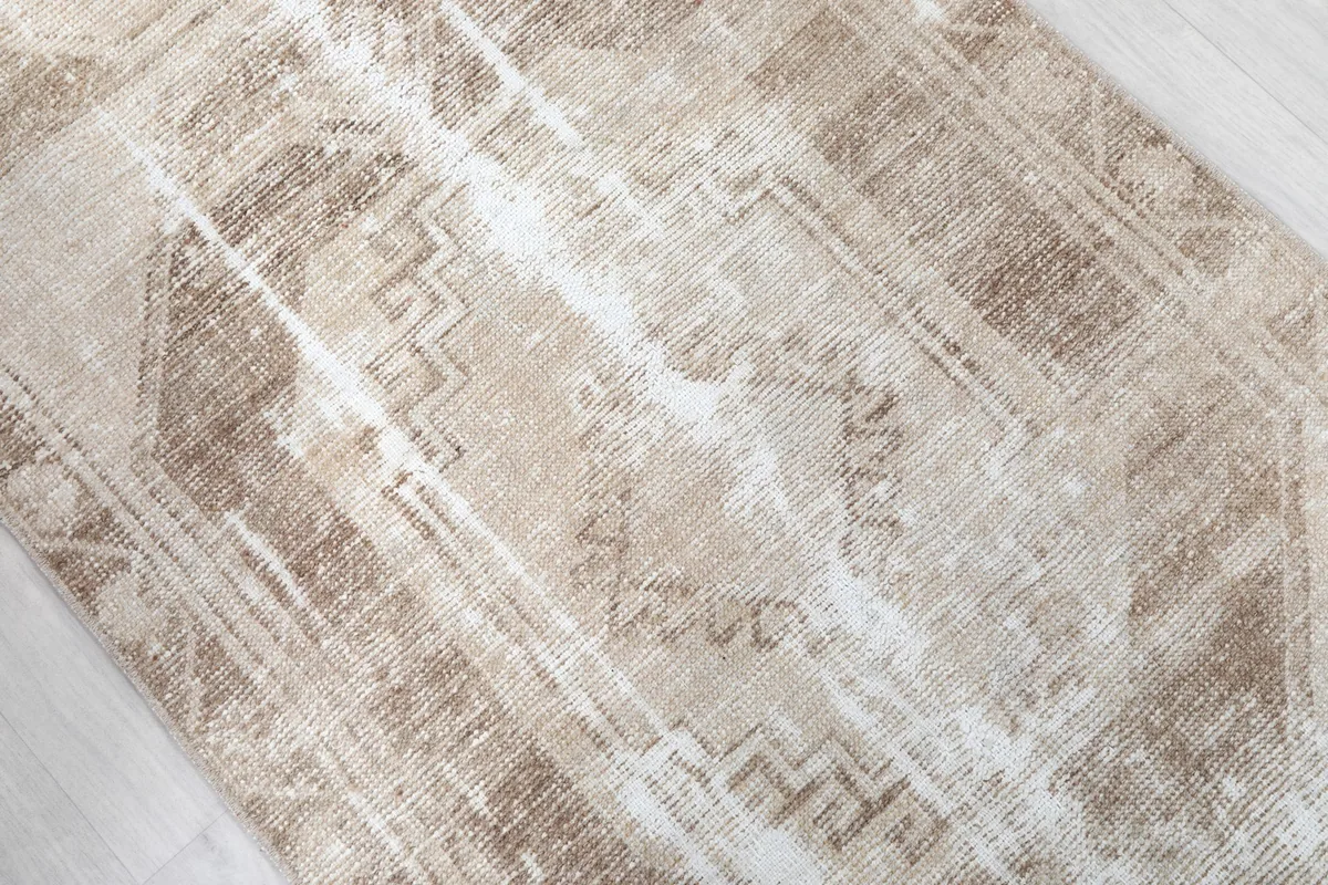 Overhead close-up showing the intricate geometric motifs and varying shades of beige, tan, and brown in the pile.