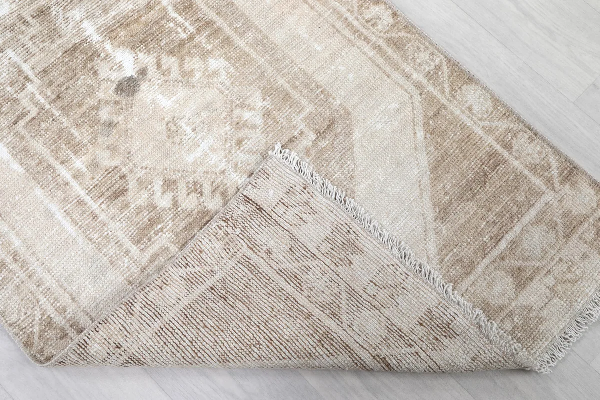 Corner of the rug folded to show the hand-knotted wool pile on a cotton foundation, with visible fringe.