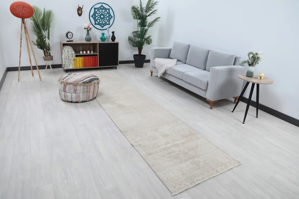 Angled view of the beige runner rug complementing a light gray sofa and striped ottoman