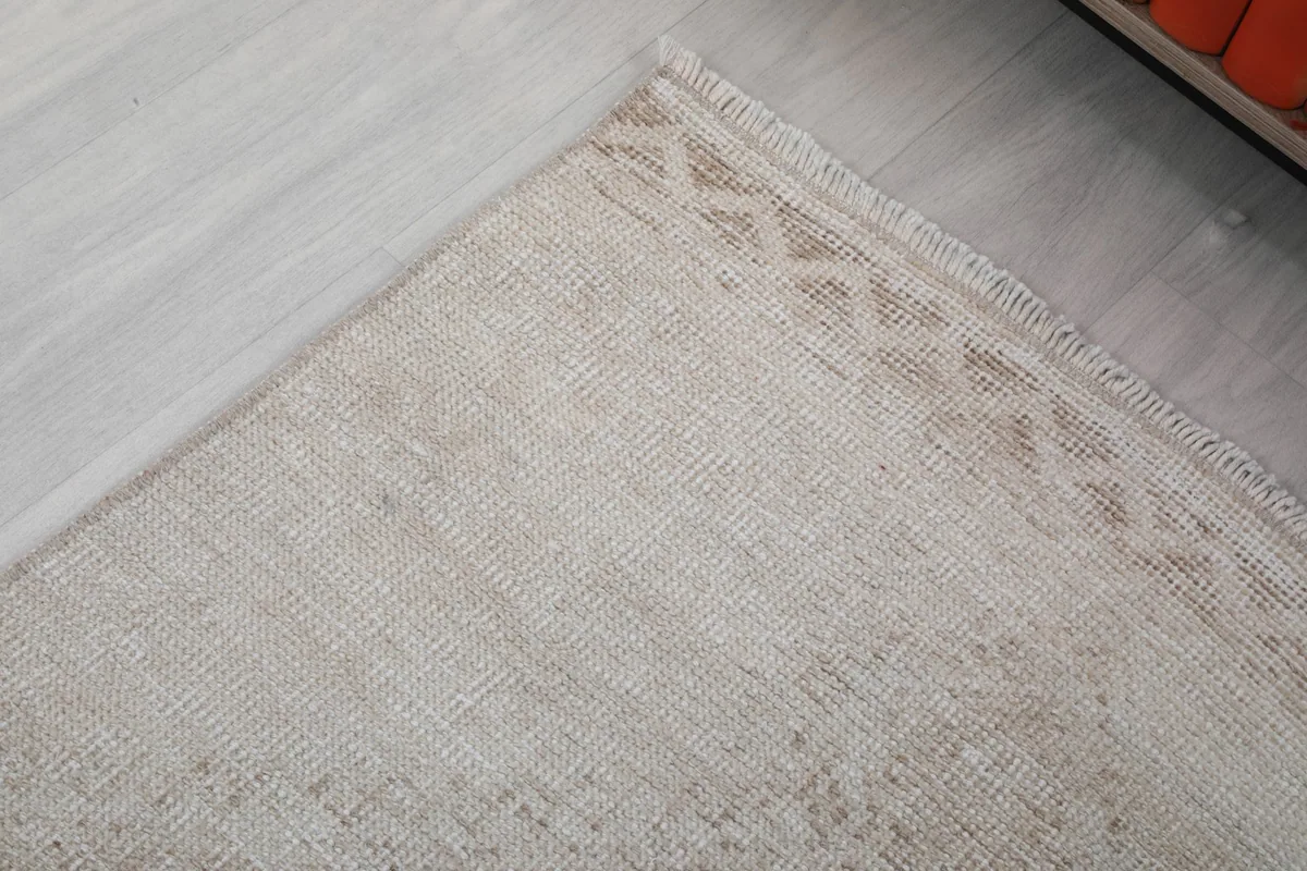 Detail of the border design and corner of the beige runner rug, showing slight wear