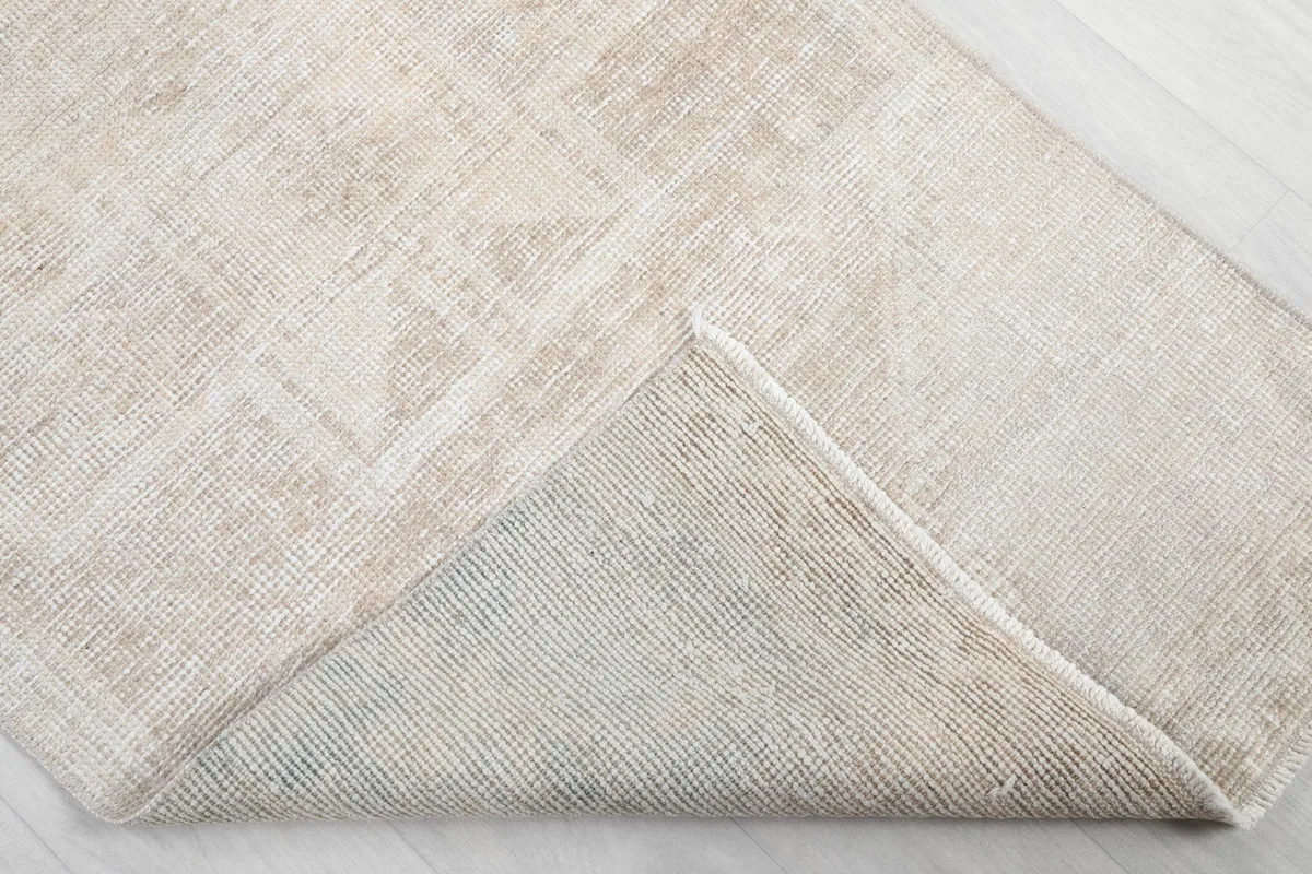 Corner of the rug folded back, revealing the wool pile and cotton foundation