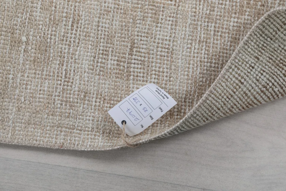 Corner of the rug with a label, showing the hand-knotted wool on cotton construction