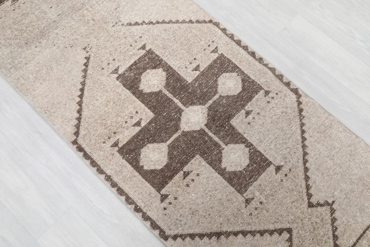 Overhead angle shot focusing on the central geometric motif and the subtle color variations of the rug.