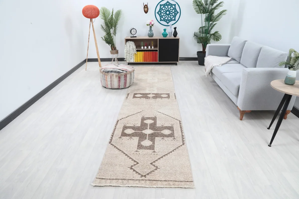 Vintage runner rug in a modern living space with light walls and a gray sofa, showing its full length.