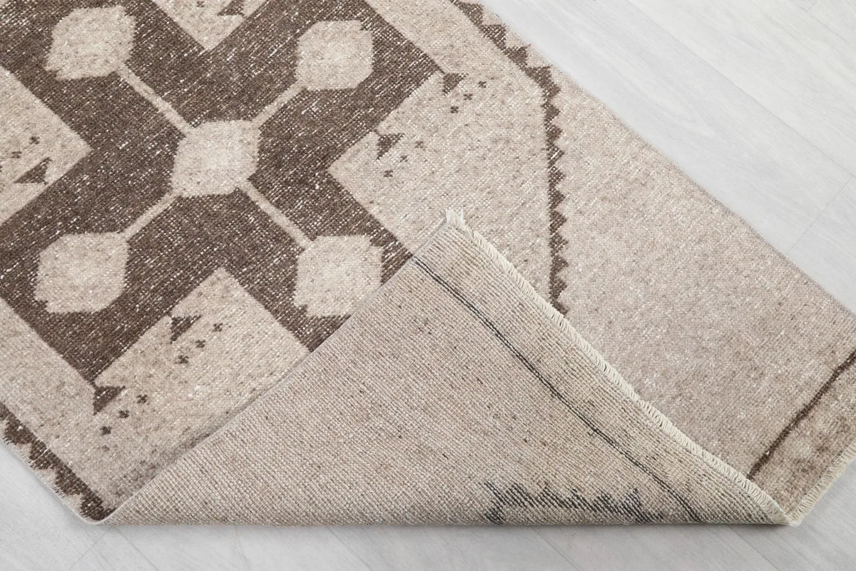 Folded corner of the runner rug, revealing the cotton foundation and the reverse side of the hand-knotted construction.