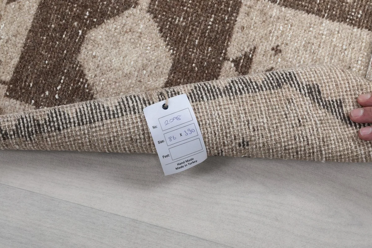 Detail of the rug tag, showing size and origin, with the rug's back texture visible.