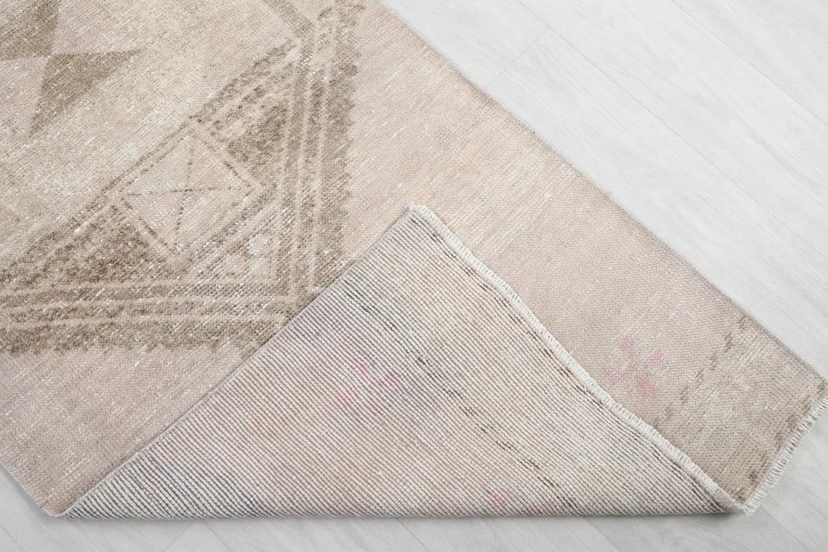 Corner of the rug folded back to show the wool pile and cotton foundation