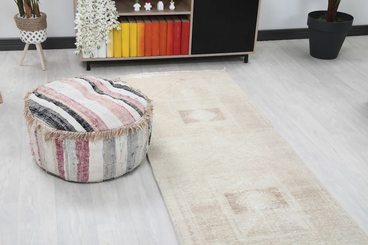 Close-up of the runner rug next to a striped ottoman and a colorful bookshelf
