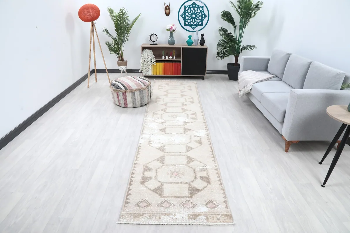 Vintage Anatolian runner rug displayed in a living room setting with a light sofa and pouf