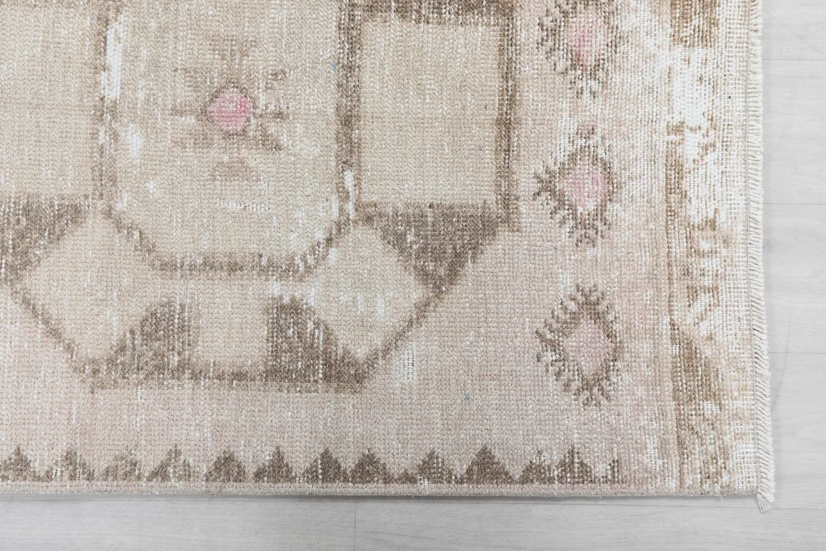 Detailed view of the rug's corner with geometric patterns and subtle rose accents