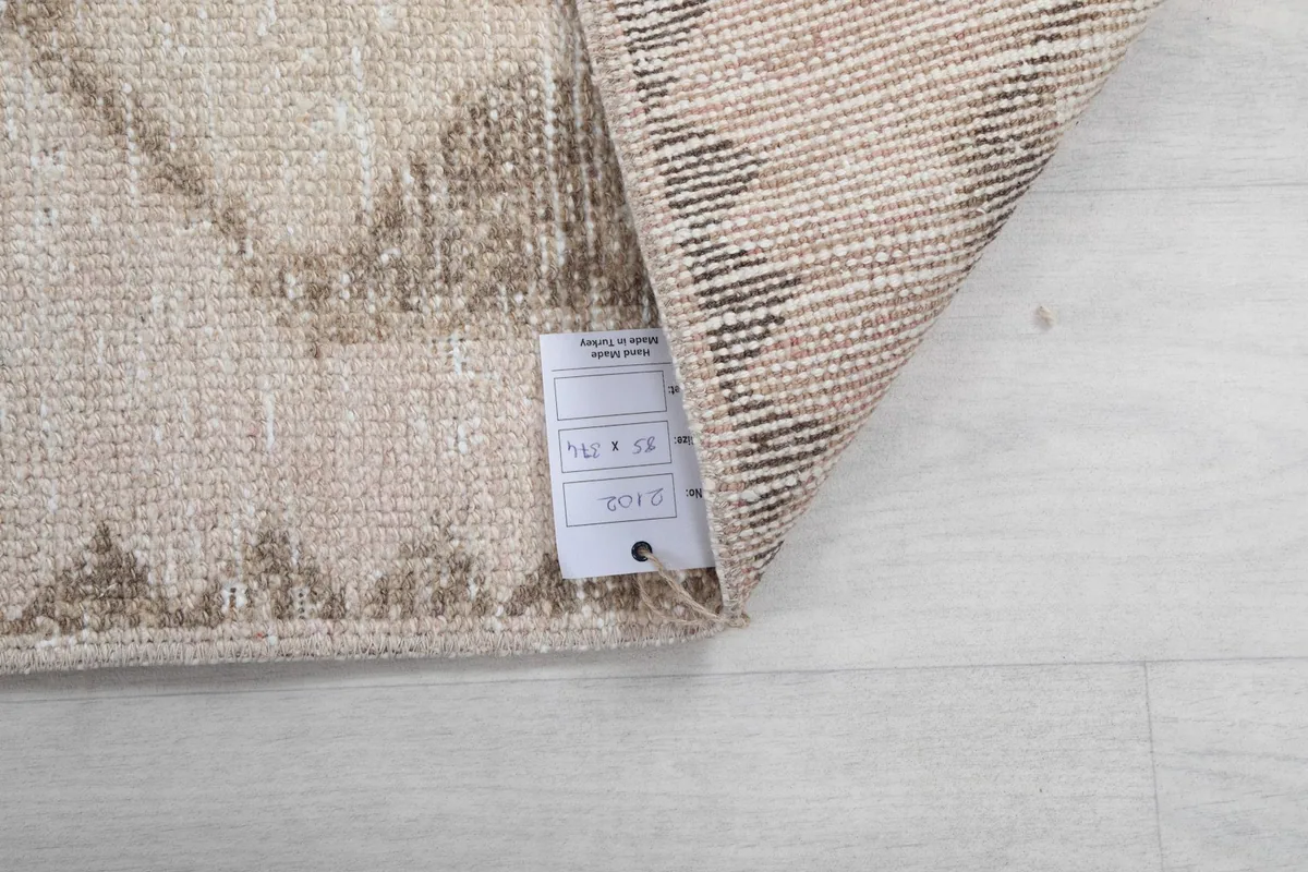 Close-up of the rug's label with size information, showing the hand-knotted back