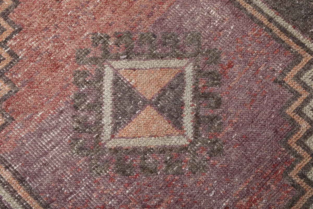 Macro detail of the faded wool pile and the geometric center of a medallion, showing texture.