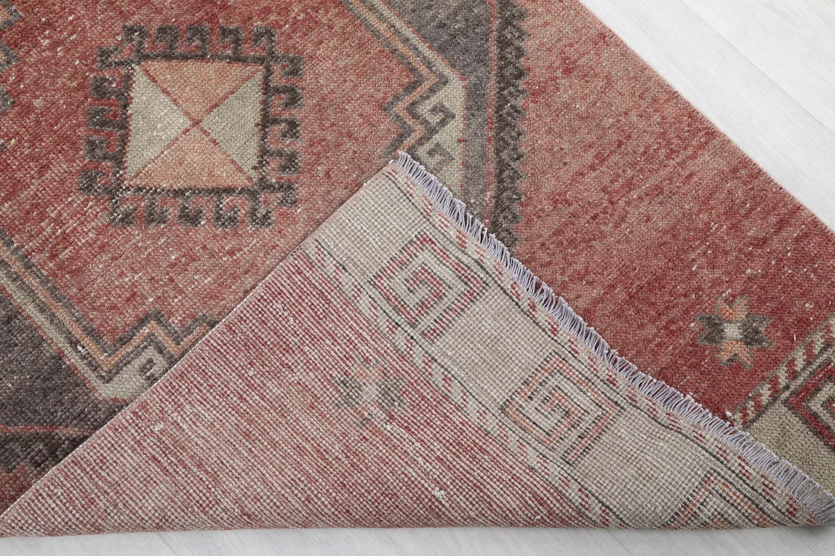 View of the rug's corner lifted to reveal the hand-knotted cotton foundation and the reverse side.