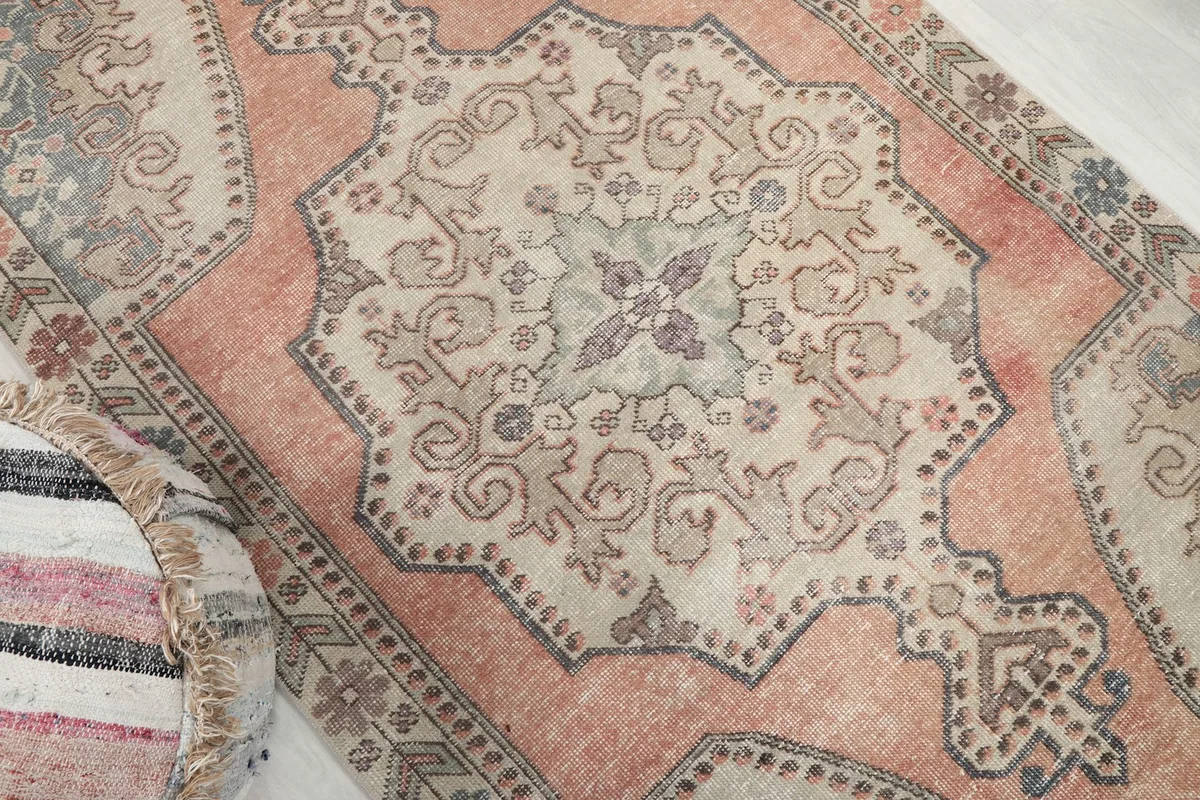 Overhead angle showing the central beige medallion and surrounding rust field of the hand-knotted rug.