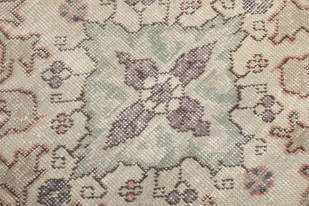 Close-up of the central motif within the medallion, showing purple and green accents.
