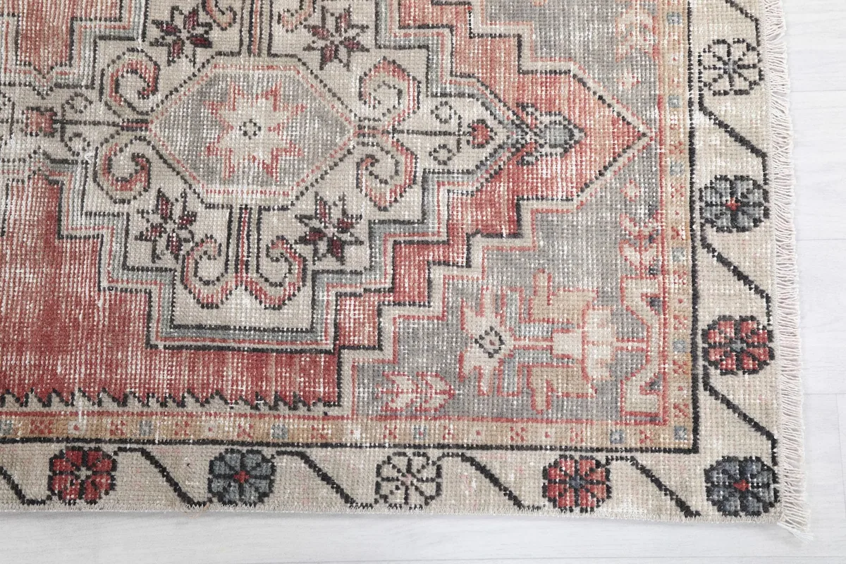 Detailed view of the rug's central geometric motif and the beige border with floral designs.