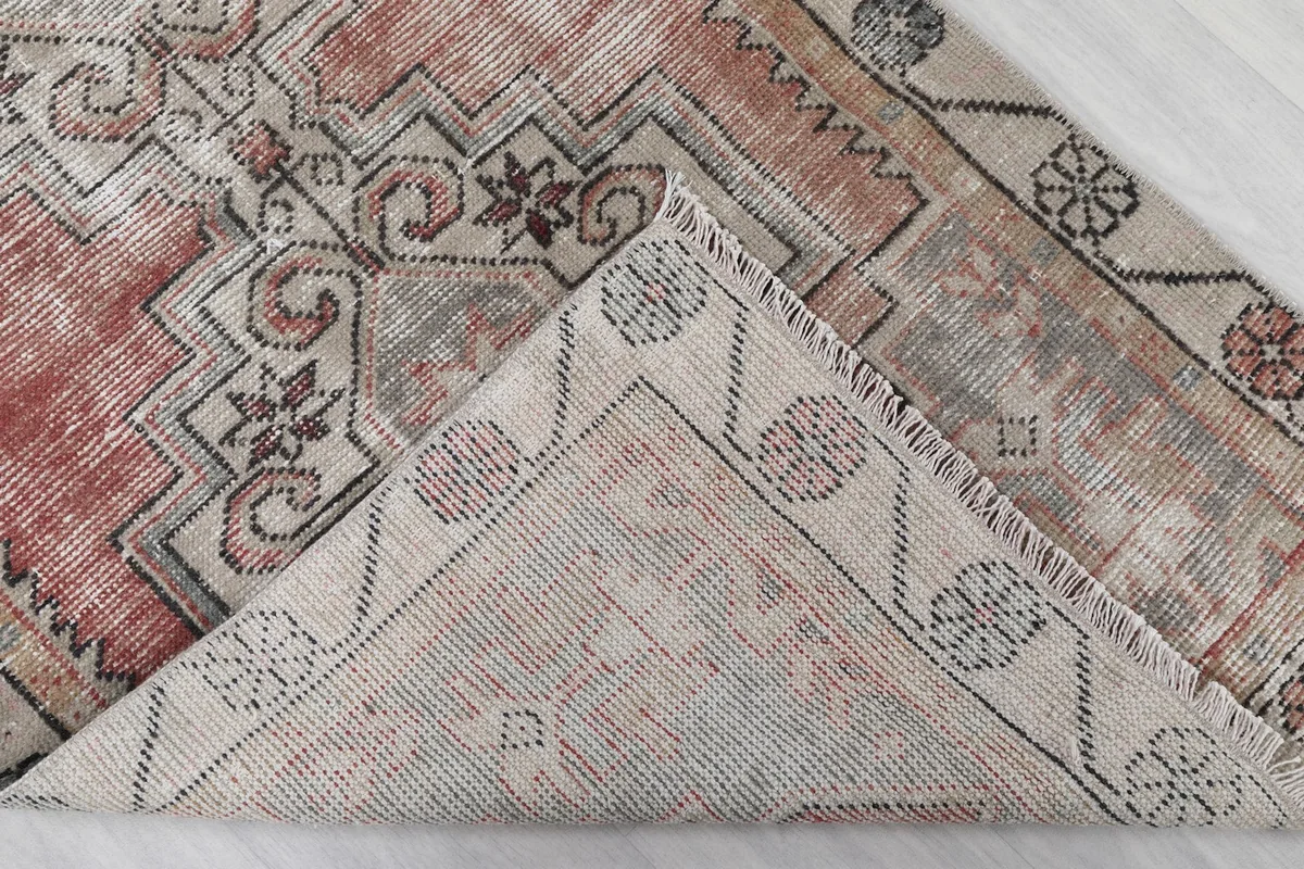 Corner of the rug folded back to reveal the cotton foundation and the reverse side of the hand-knotted construction.