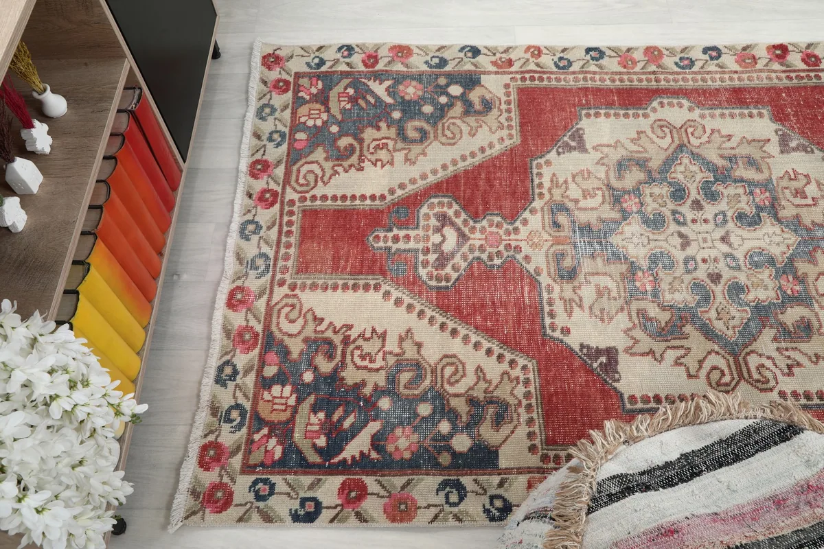 Angle view of the rug's patterns and colors from one side, next to a pouf