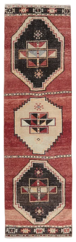 Top-down view of the 3'0" x 10'3" vintage Anatolian runner rug with red field and black, beige geometric patterns
