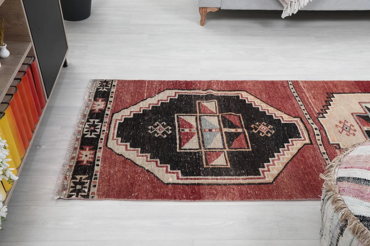 Angled shot of the rug's end section, showing the black medallion and red field