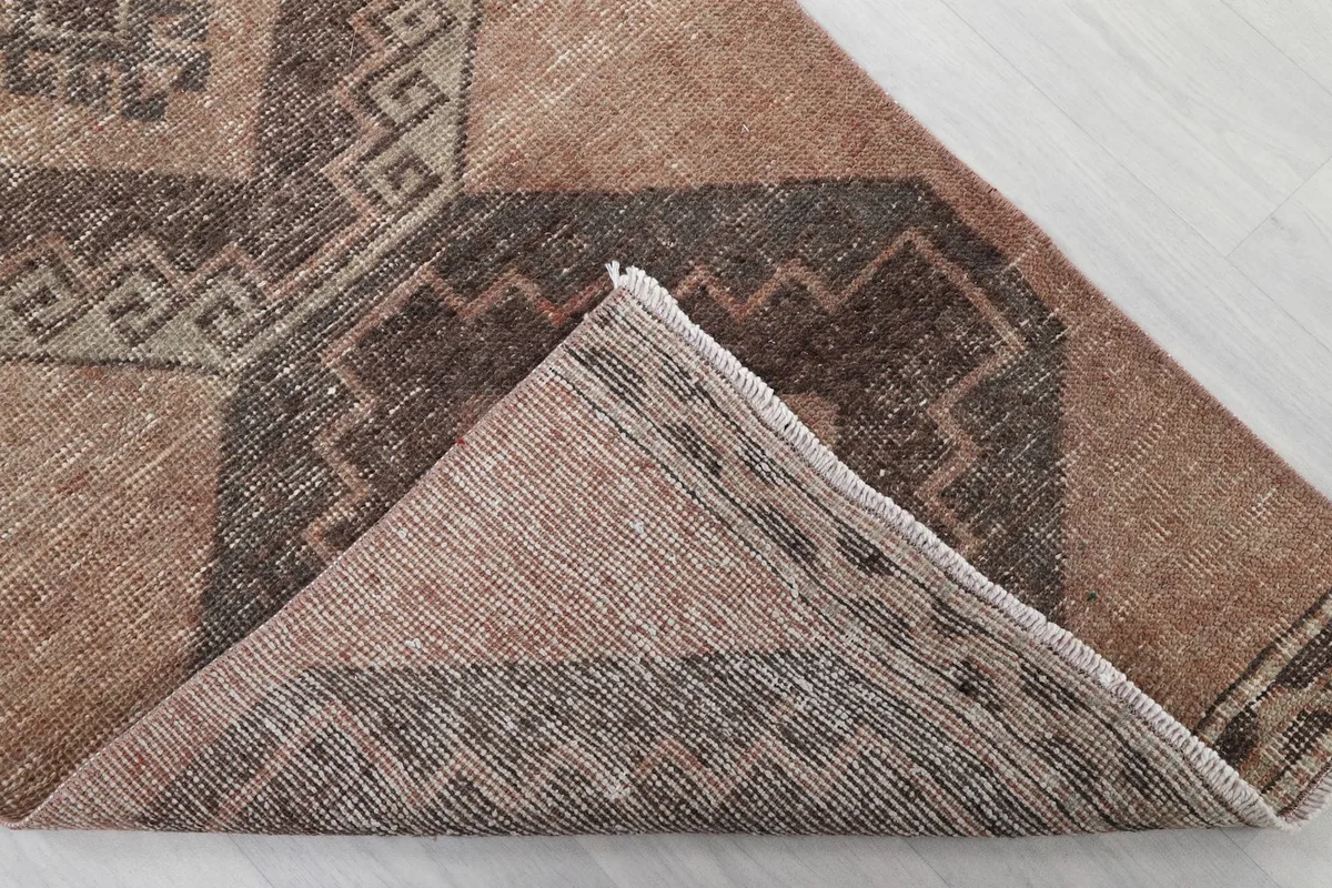 Corner of the rug folded over to show the hand-knotted wool pile and cotton foundation from the back.