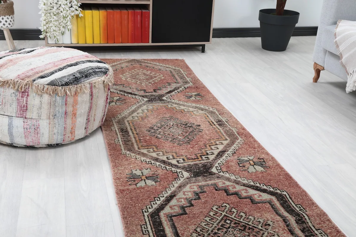 Close-up angle shot of the rust and black runner rug, highlighting the central geometric patterns and colors.