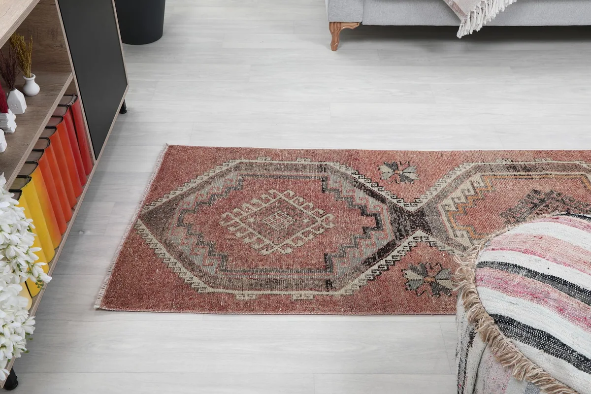 Low angle view of the rust and black runner rug extending down a hallway, showing its narrow profile.