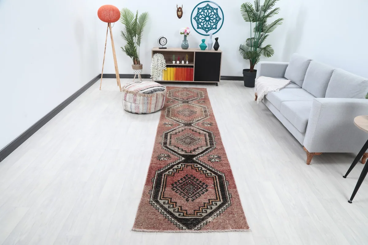 Vintage rust and black geometric runner rug displayed in a modern hallway with light flooring and furniture.