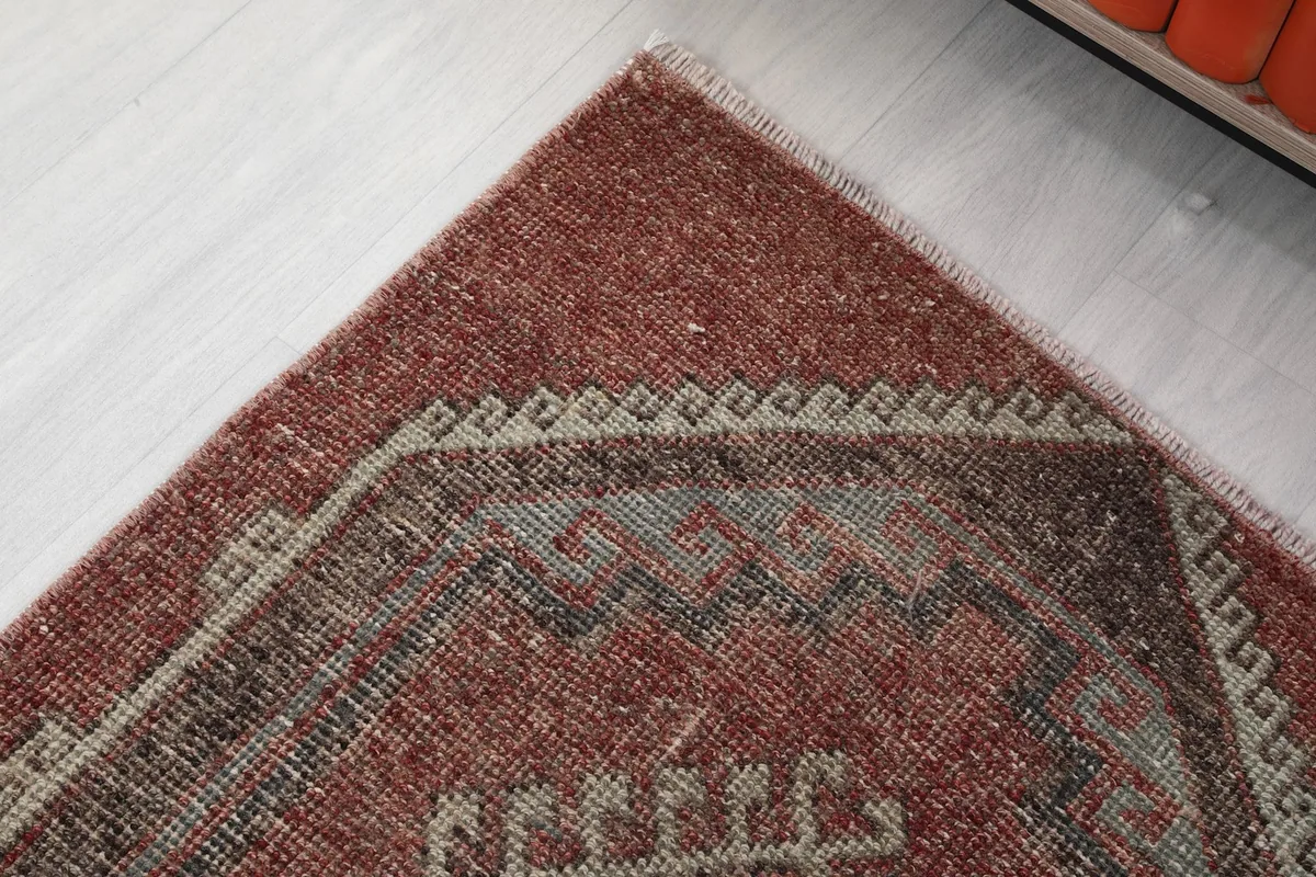 Corner detail of the rust colored field and a gray geometric border element on the hand-knotted rug.