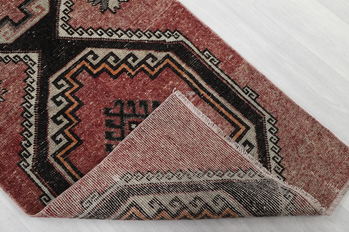 Folded corner of the rug revealing the back of the hand-knotted wool pile and cotton foundation.
