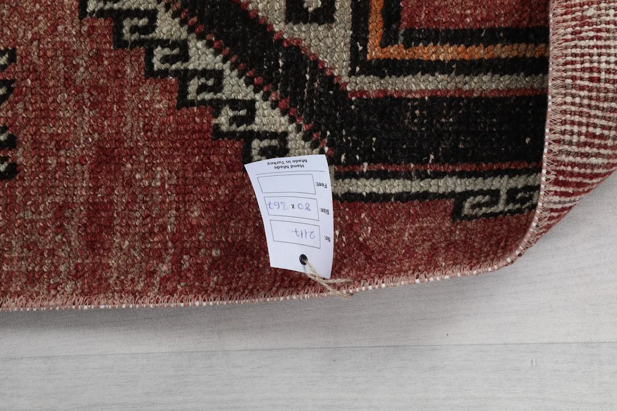 Close-up of the rug's surface with a product tag, showing the texture and color of the vintage wool.