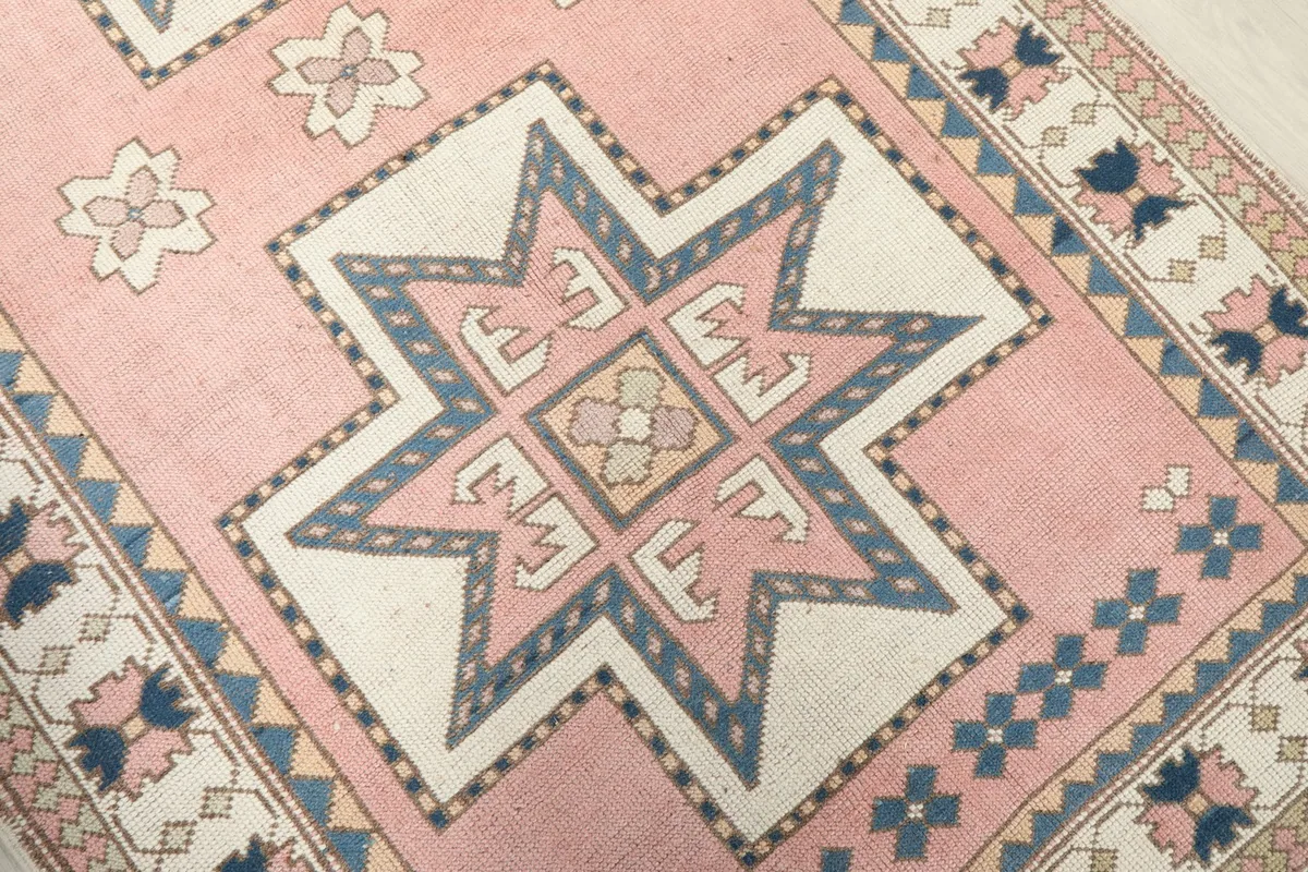 Close-up of a main geometric star motif on the rose field, highlighting the blue and ivory colors.