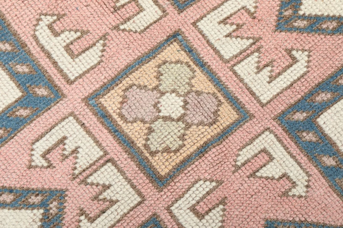Extreme close-up of the hand-knotted wool pile, showing texture and subtle color variations within a star motif.