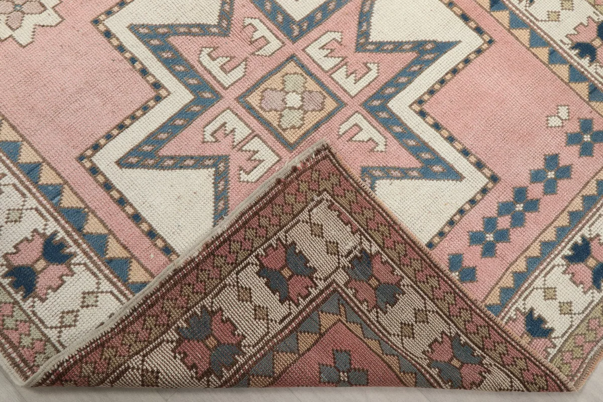 Corner of the rug folded back to reveal the cotton foundation and the reverse side of the hand-knotted wool.