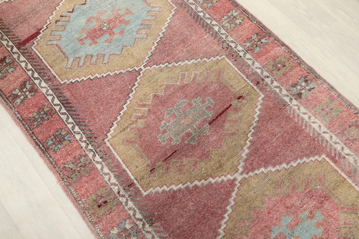 Angled view of the rug's central motifs, highlighting the rose and tan color transitions