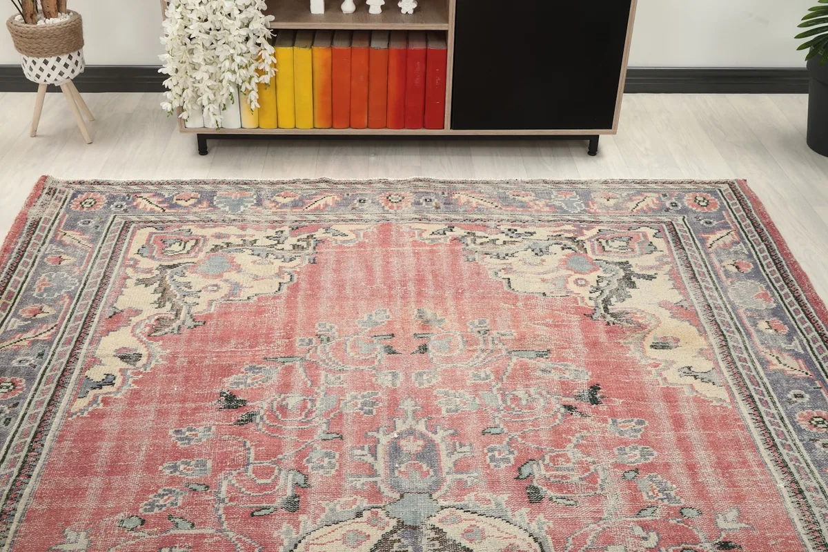 View of the rose vintage rug in a room, highlighting the distressed appearance and colors