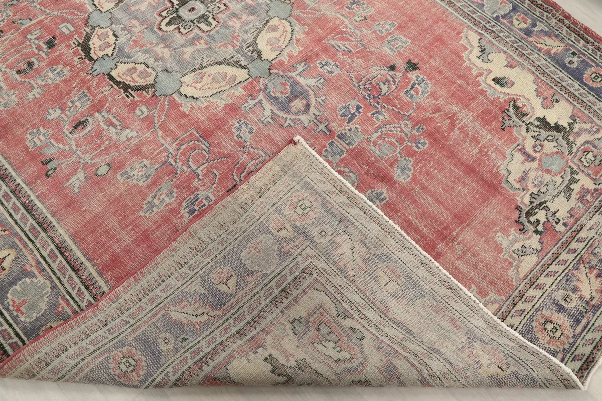 Corner of the rug folded back, revealing the reverse side of the hand-knotted construction