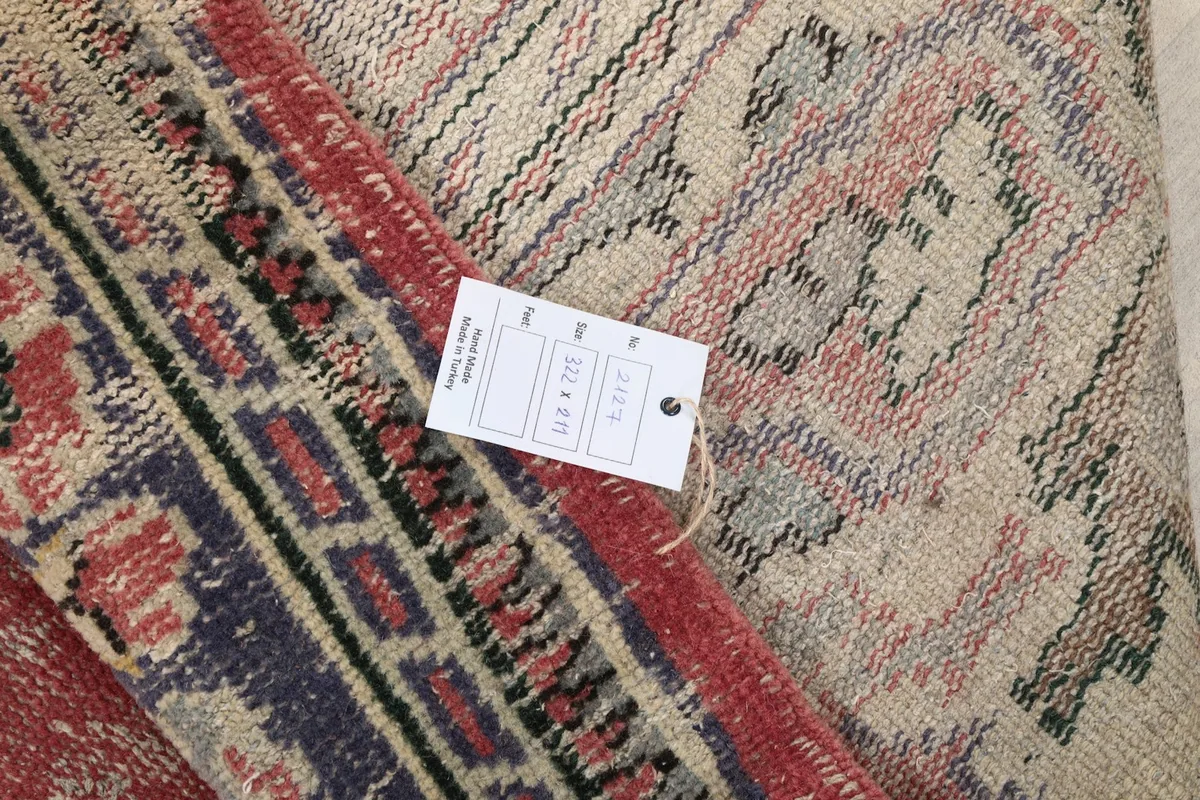 Folded rug corner with a size tag showing dimensions 211 x 322 cm and 6'11" x 10'7"