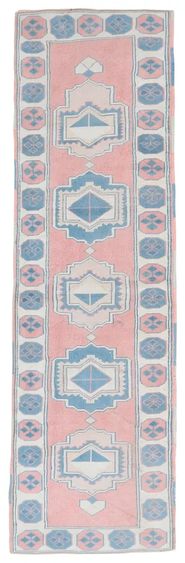 Full overhead view of the rose and blue geometric Anatolian runner on a white background