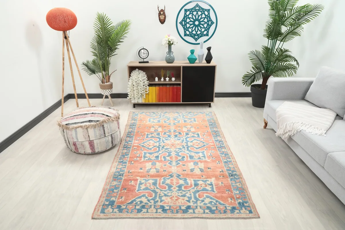 Vintage rust and blue rug displayed in a living room setting with a sofa and decor.