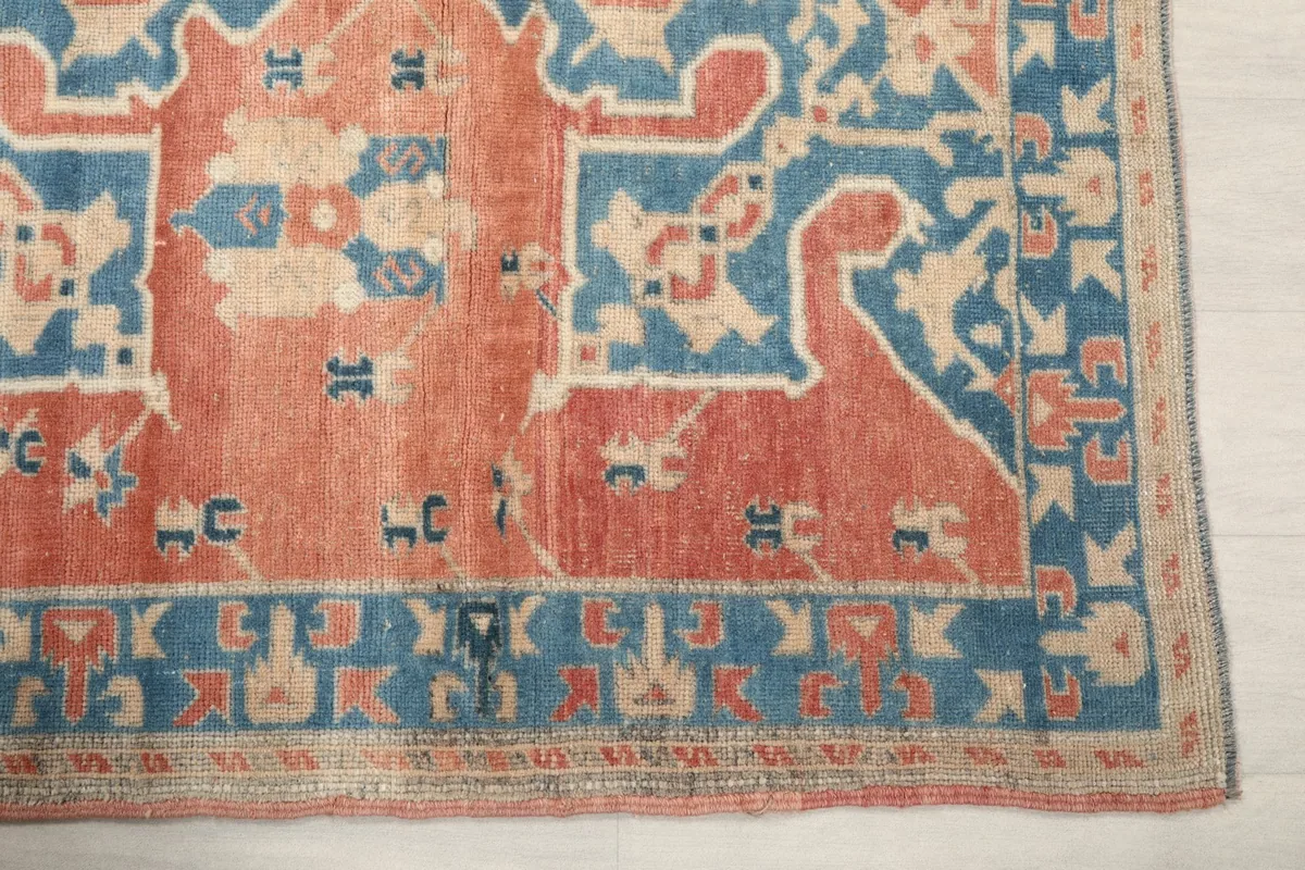 Detail of the blue border and rust field of the hand-knotted vintage rug.
