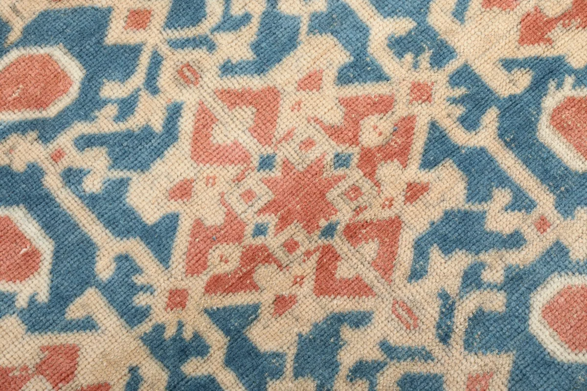 Extreme close-up of the low wool pile and hand-knotted texture of the rug.