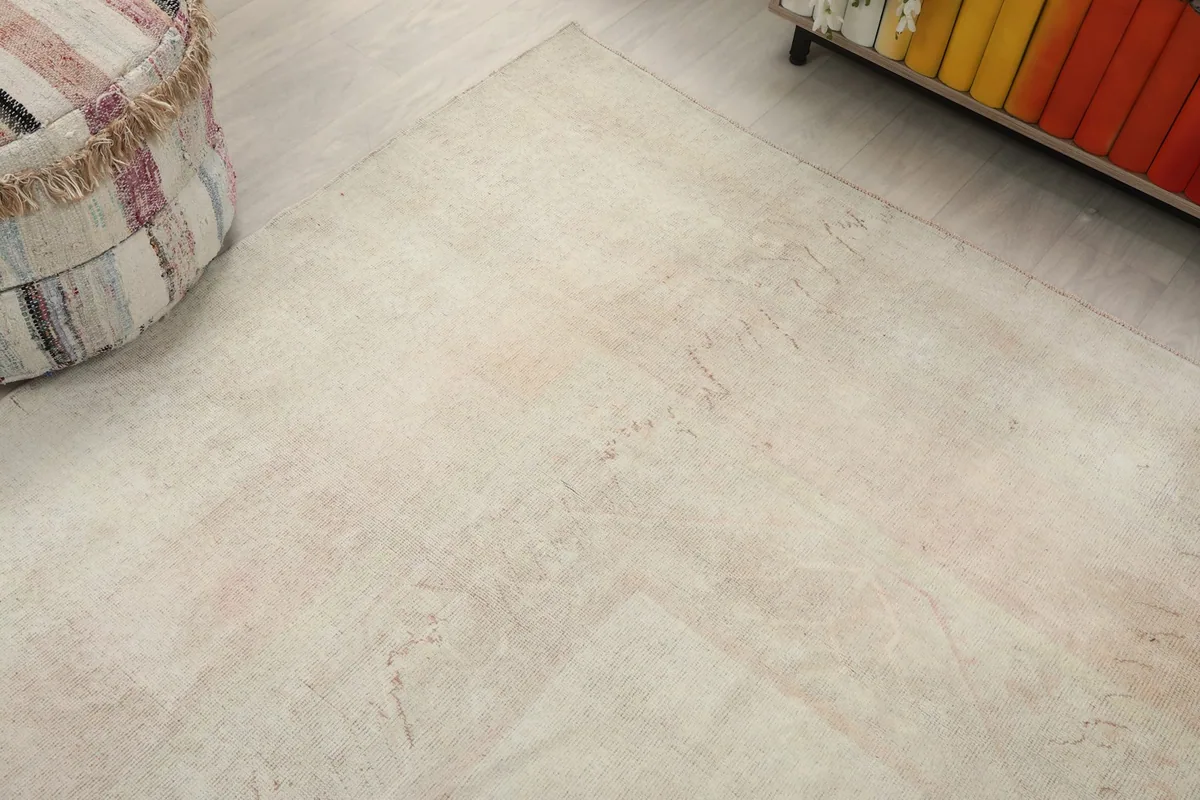 Corner view of the cream and rose rug, highlighting its soft colors and texture