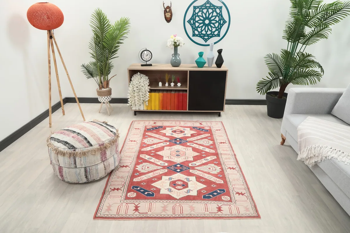 Vintage red Anatolian rug placed in a modern living room setting with a gray couch and wooden furniture.
